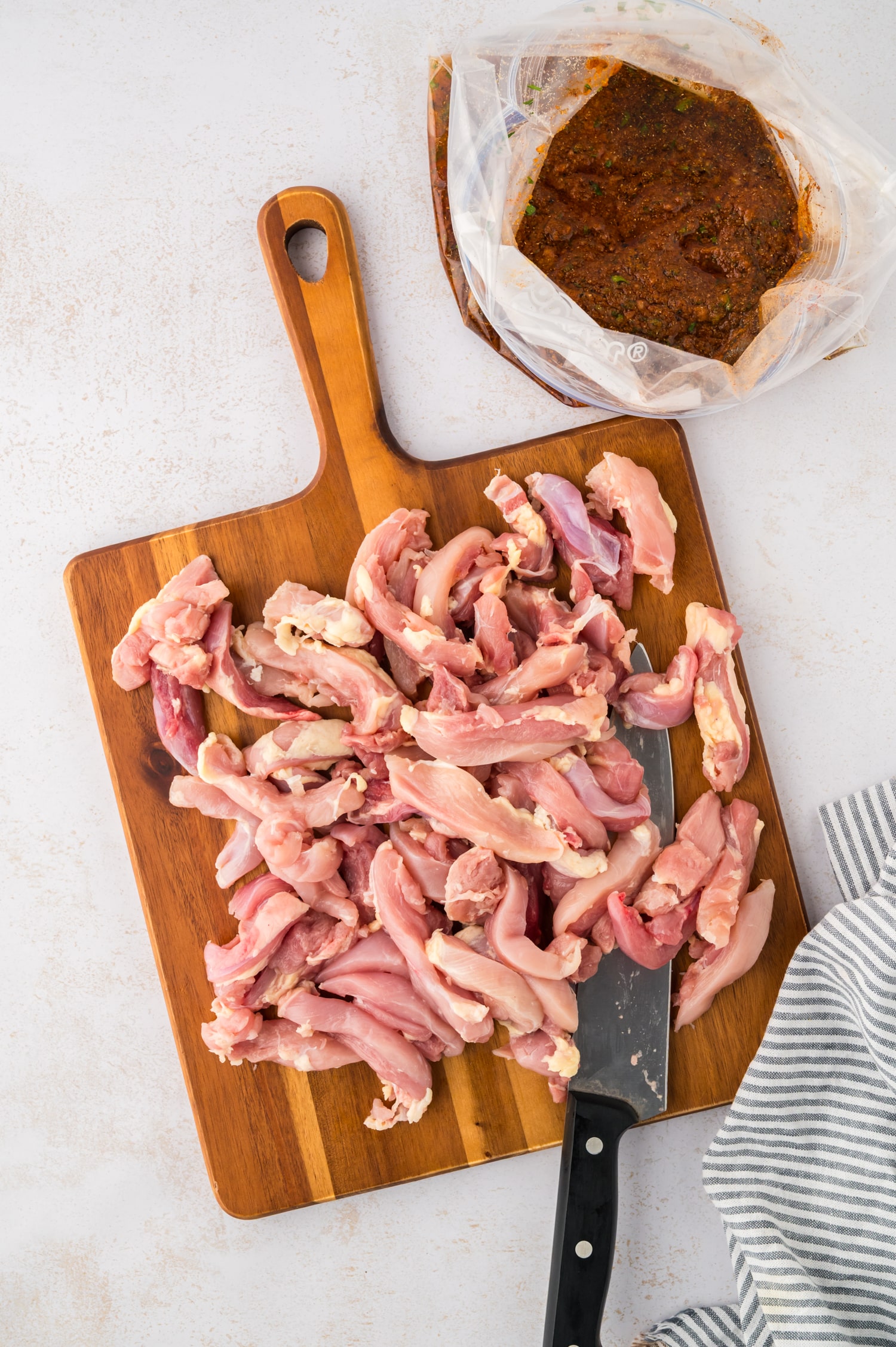 Cur raw chicken next to a freezer bag full of seasoning.