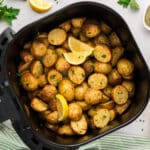 Overhead view of Greek potatoes in an air fryer basket.