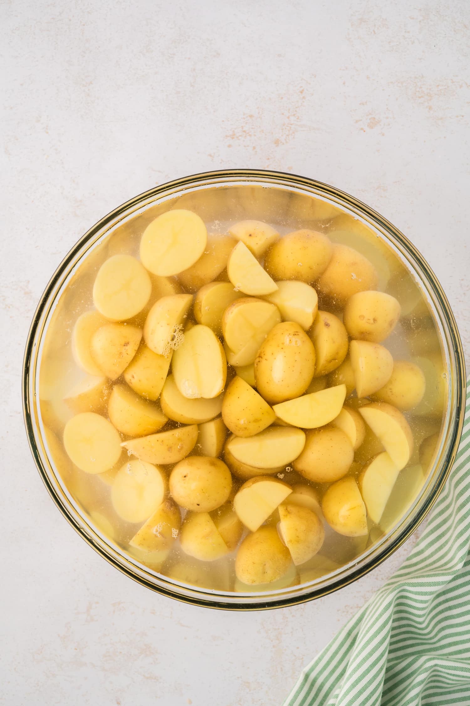 Potatoes soaking in a bowl of water.