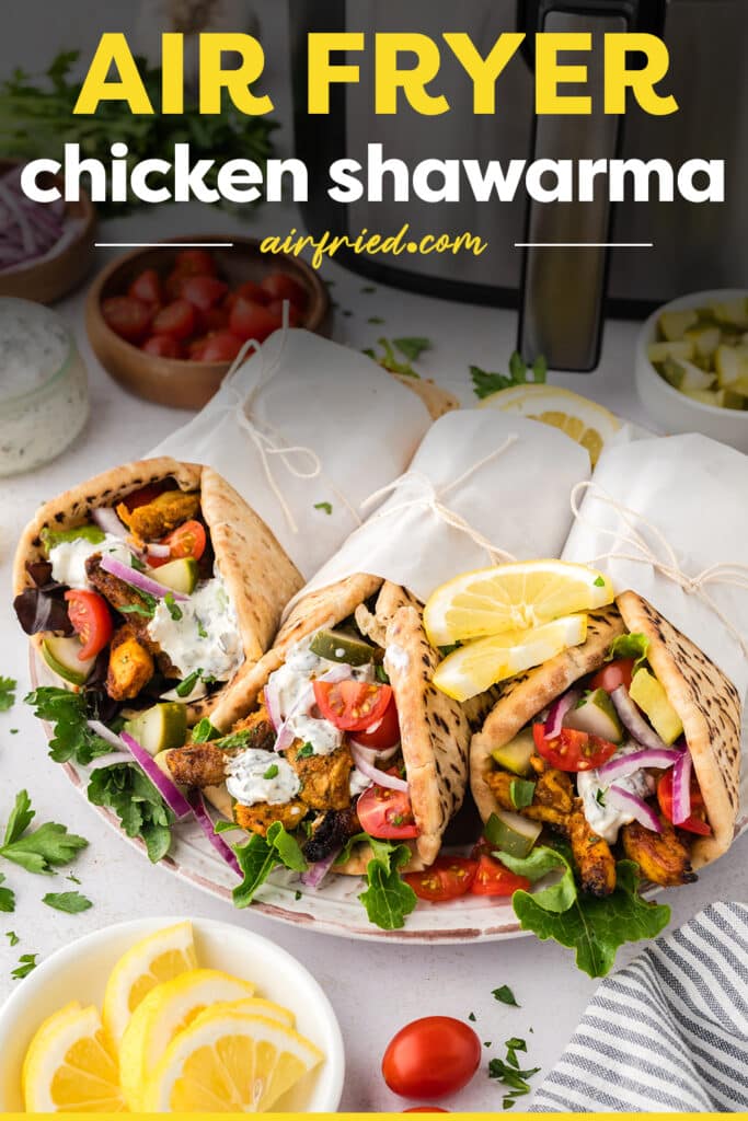 Three chicken shawarma pitas wrapped on a plate.