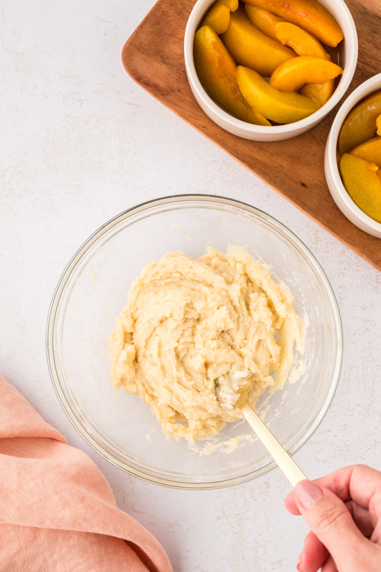 Cobbler dough is being stirred inside a clear glass bowl, forming a thick, soft mixture.