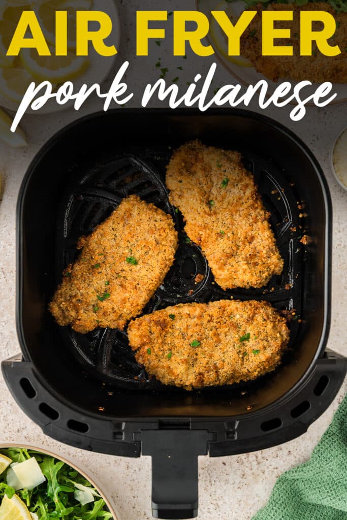 Three pieces of cooked pork milanese are arranged inside an air fryer basket.