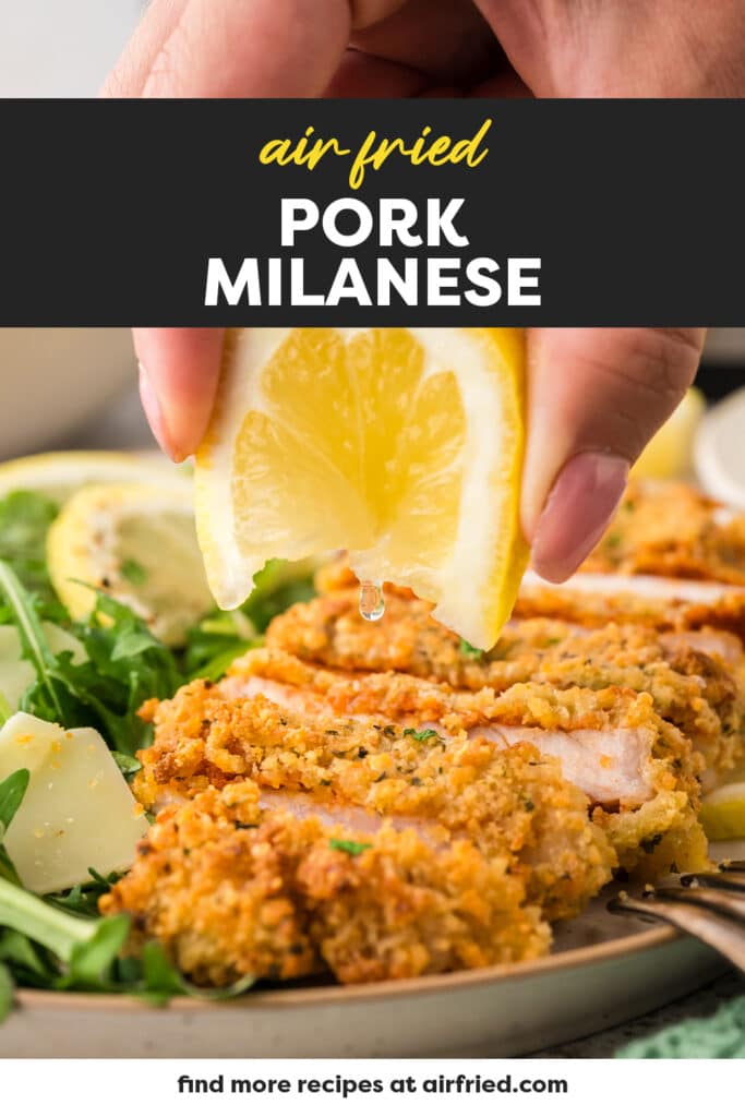 A slice of lemon is being squeezed over a piece of cooked pork milanese, adding a fresh, bright touch to the dish.