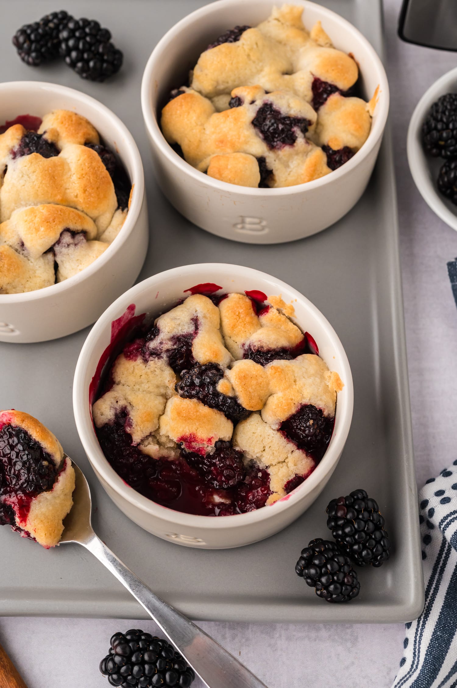 Close-up of blackberry cobbler in a ramekin with a bite scooped out.