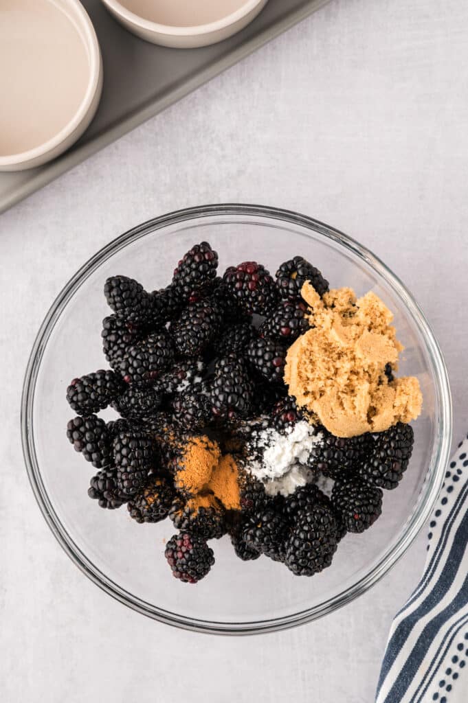 Ingredients for the blackberry filling being added to a clear glass bowl.
