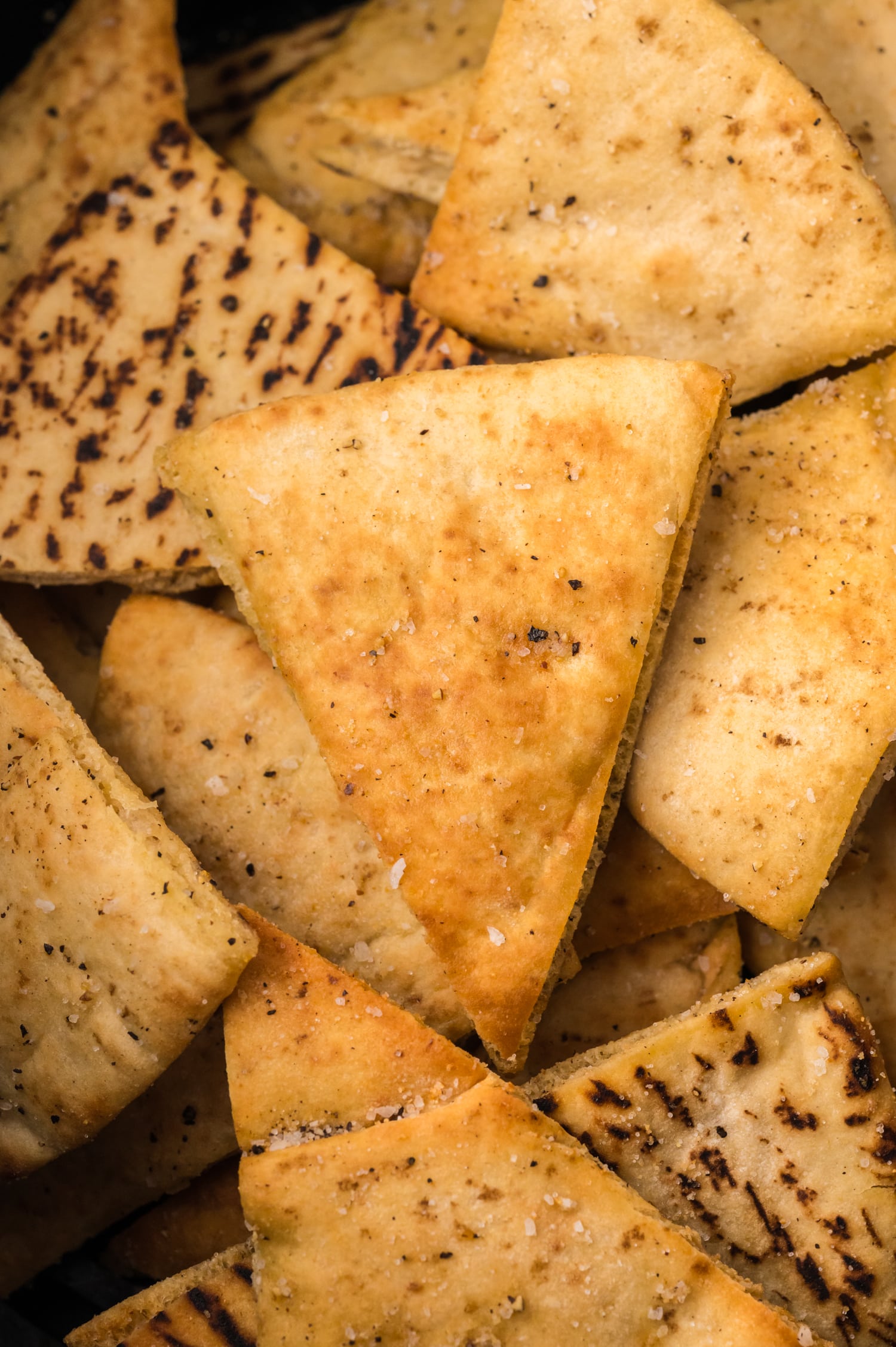 A close-up of golden-brown air fryer pita chips seasoned.