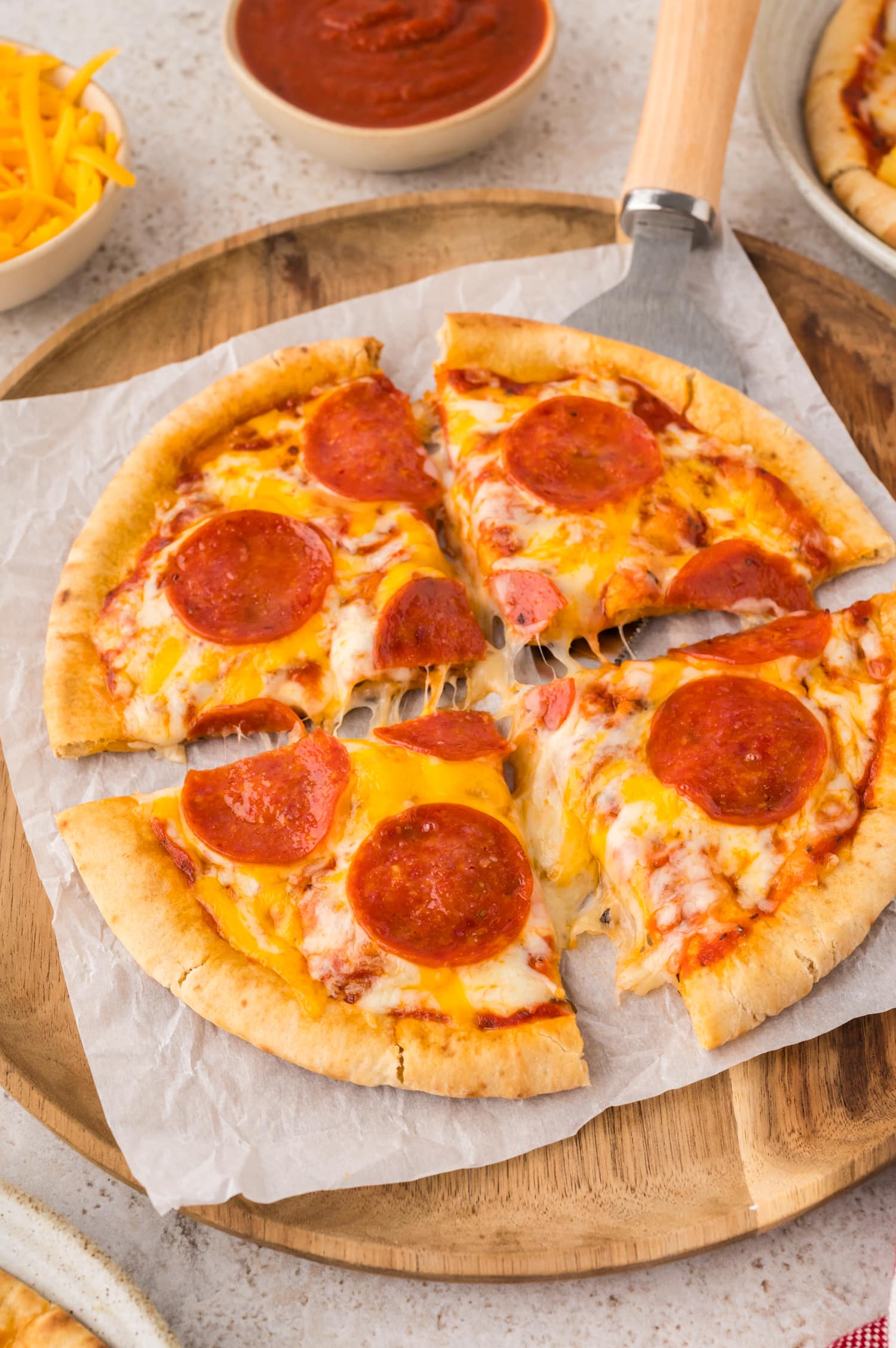 Sliced pita pizza on a wooden serving tray.