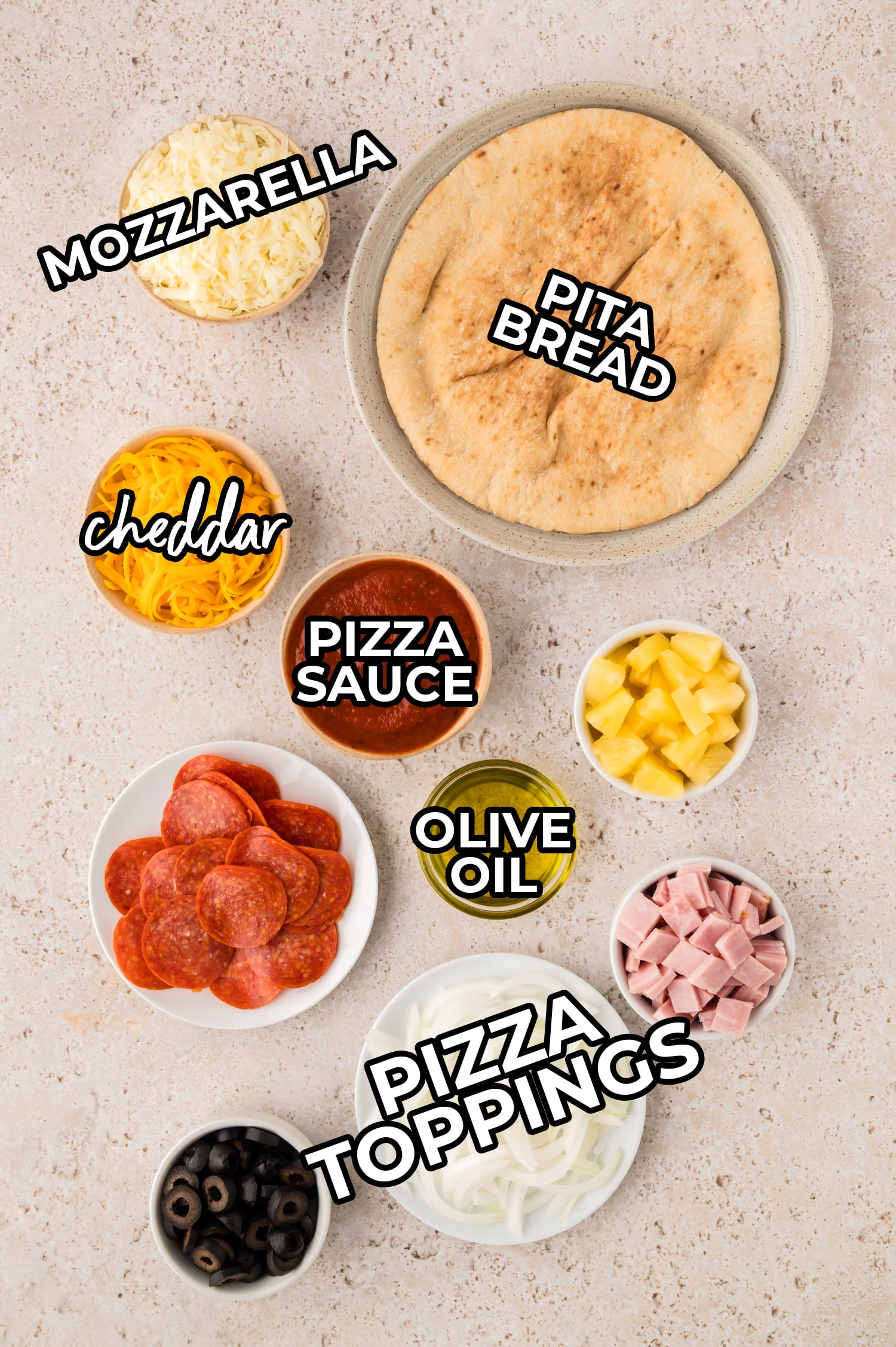 Ingredients for pita pizza spread out and labeled on a white countertop.