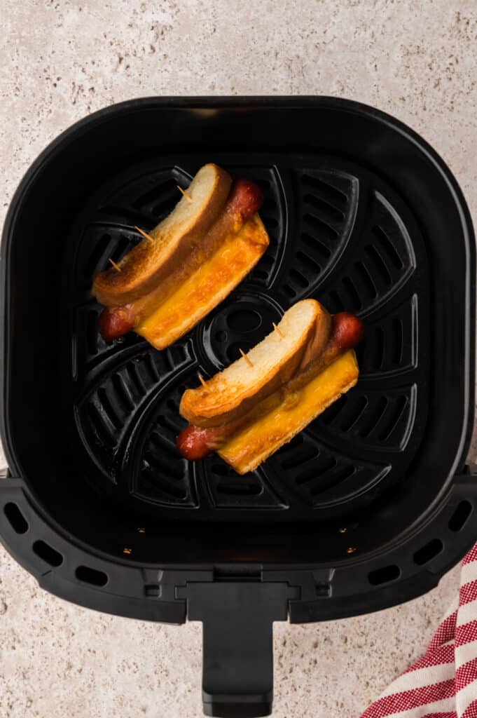 Two cooked grilled cheese hot dogs in an air fryer hot dog.