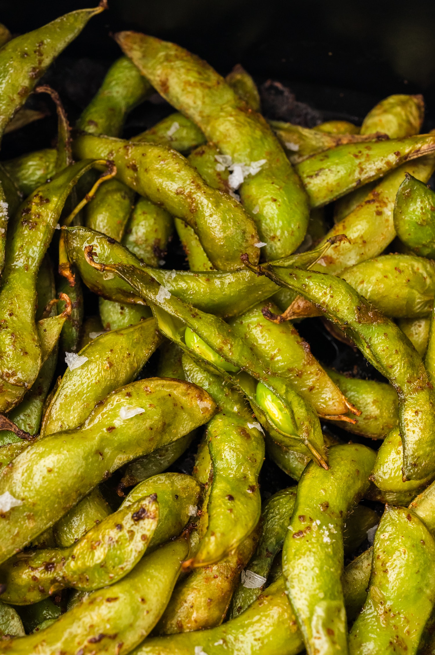 Close up of edamame in an air fryer basket.