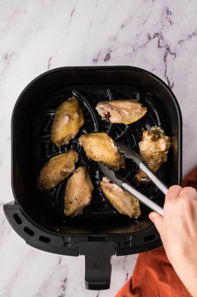Chicken wing sections in air fryer basket.