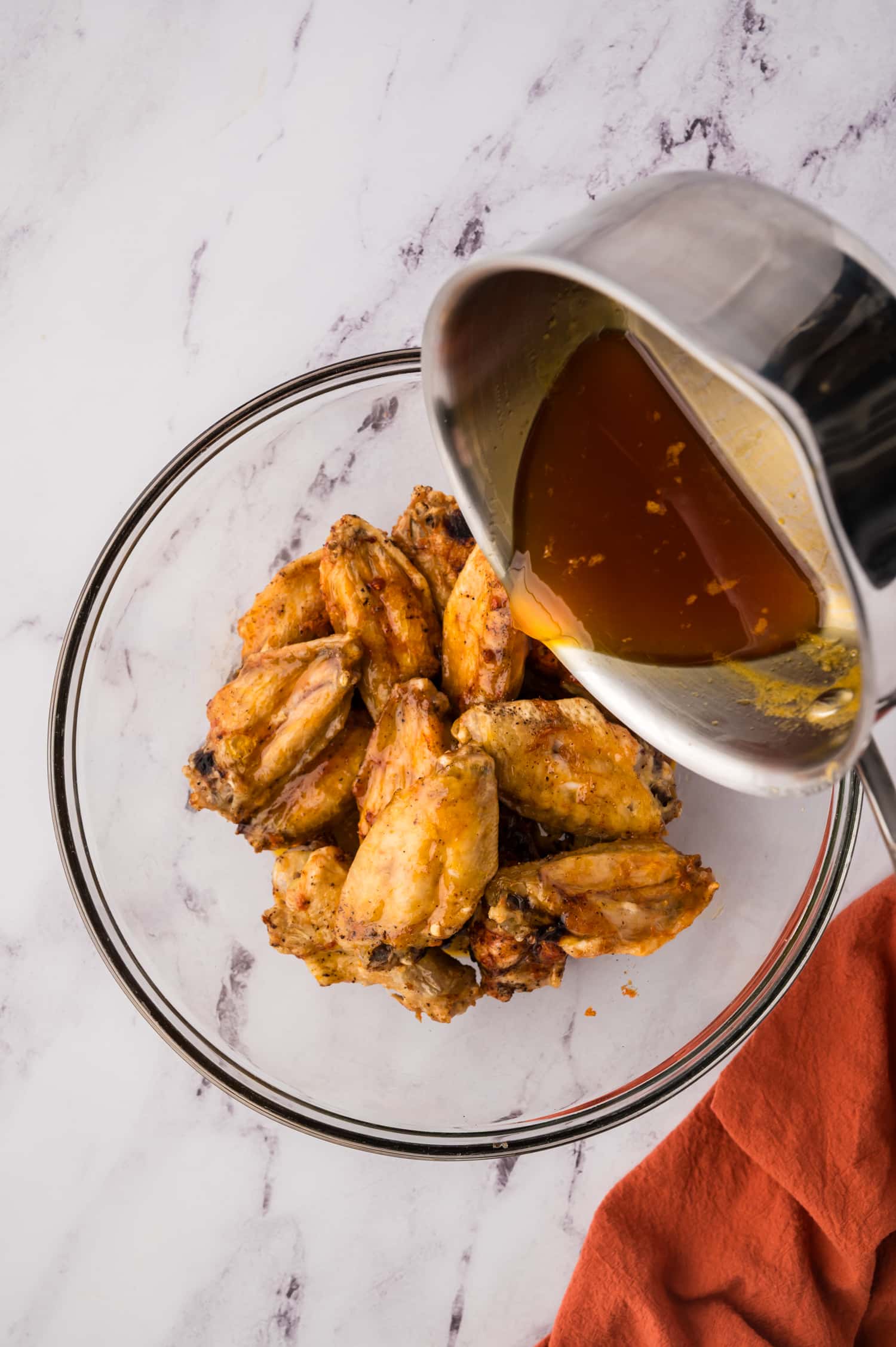Hot honey sauce being poured over wings.