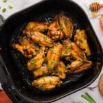 Air fryer basket full of hot honey chicken wings.