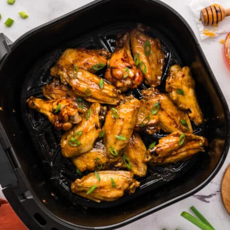 Air fryer basket full of hot honey chicken wings.