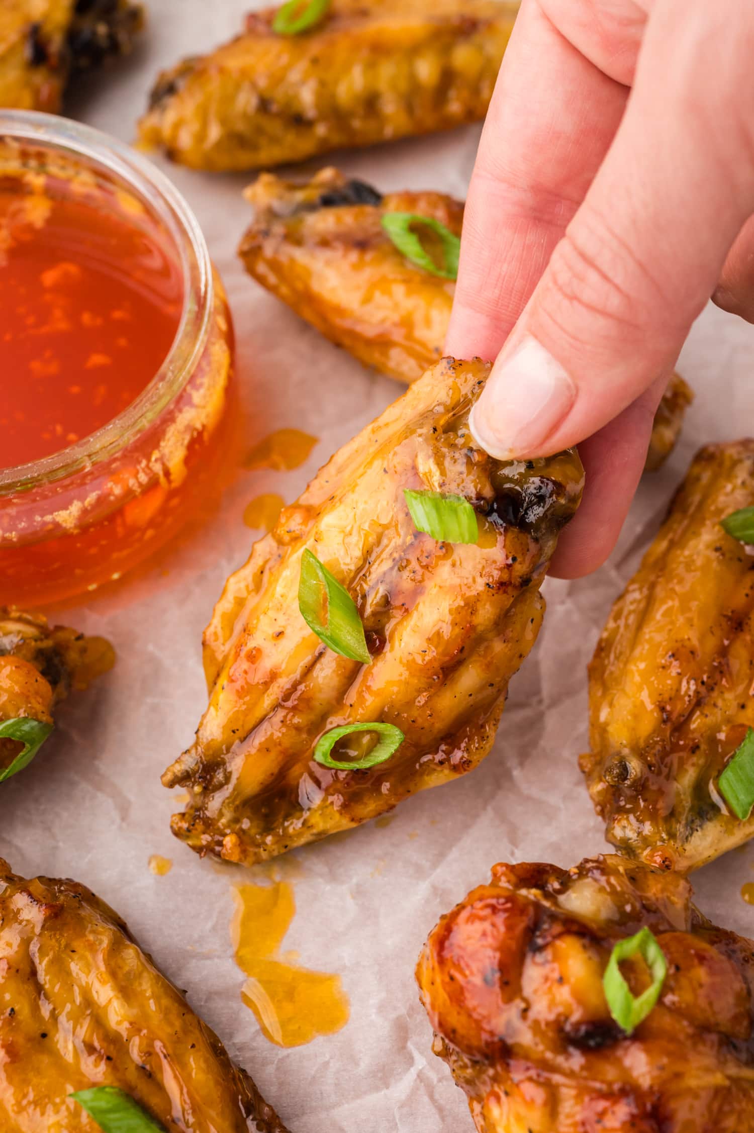 Hang picking up a chicken wing coated in hot honey.