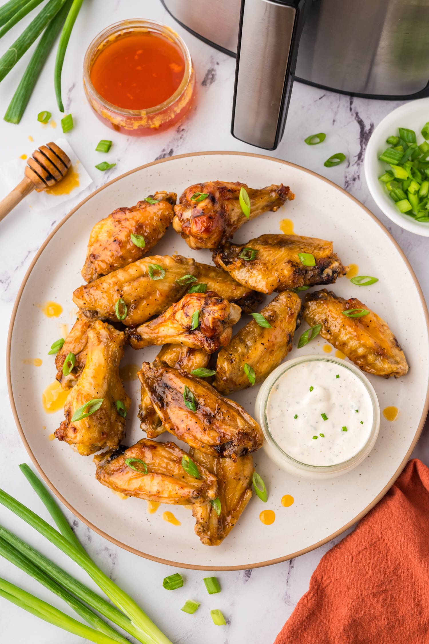 Plate full of hot honey wings with a bowl of ranch for dipping.