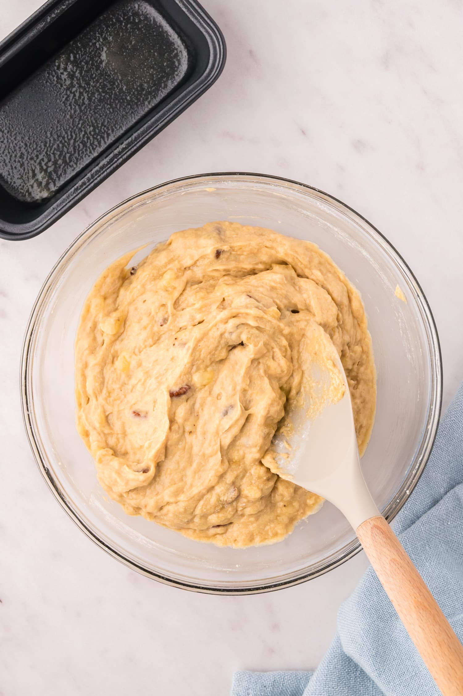 Banana bread dough in a clear glass bowl.