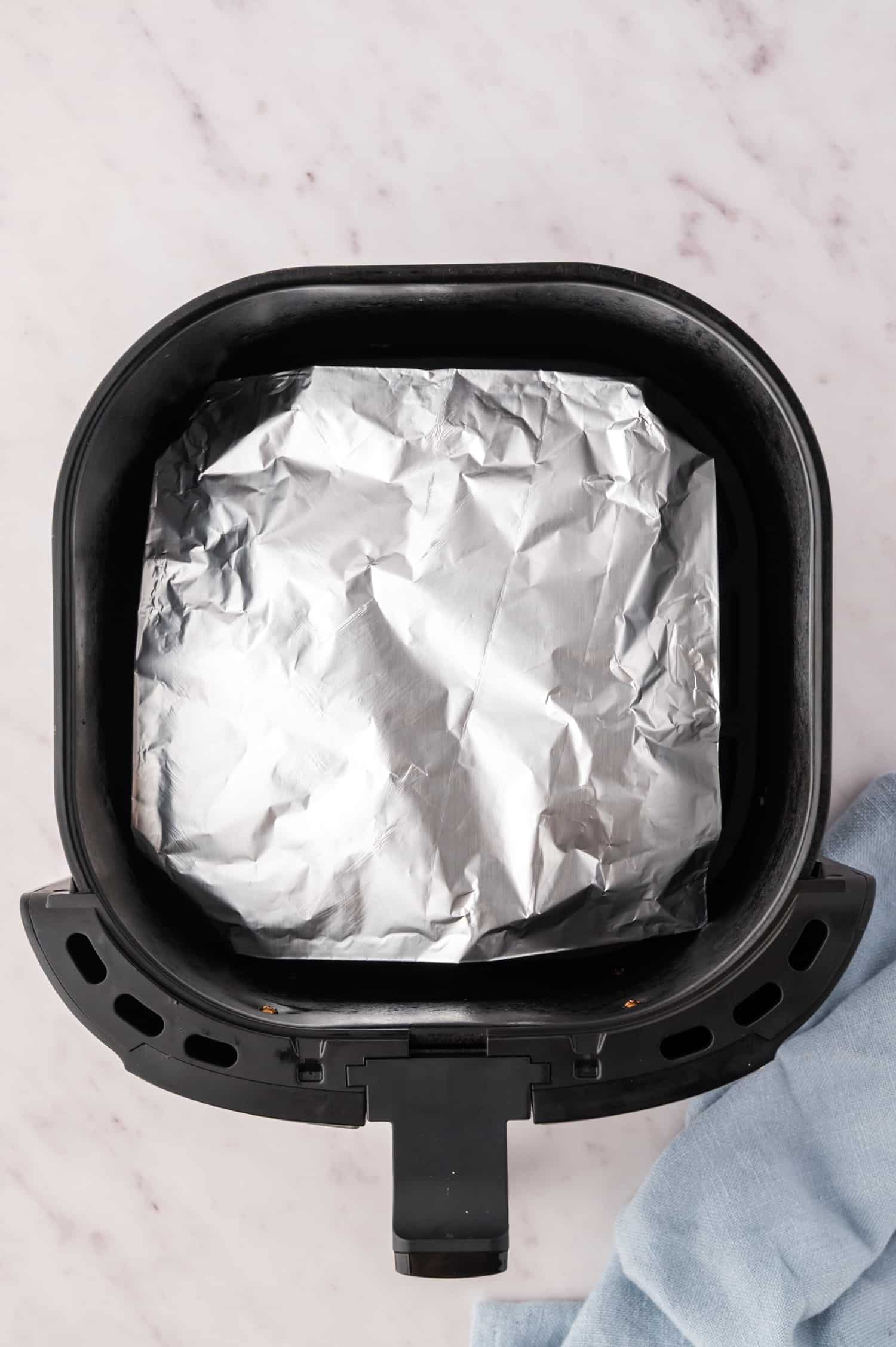 Foil covering the top of banana bread in an air fryer basket.