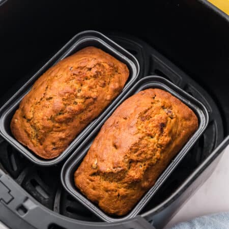 Mini banana bread loaves in an air fryer basket.