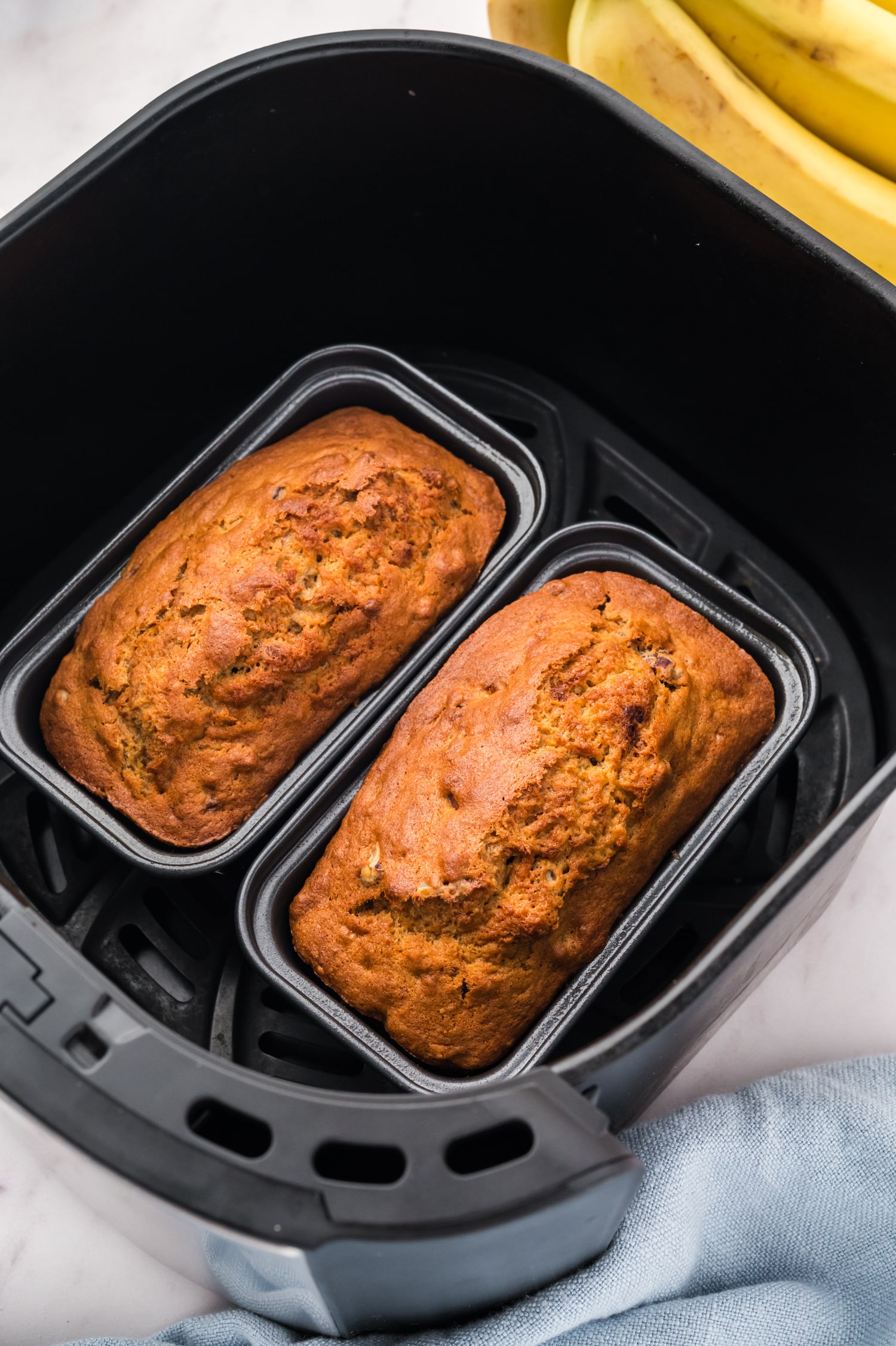 Mini banana bread loaves in an air fryer basket.