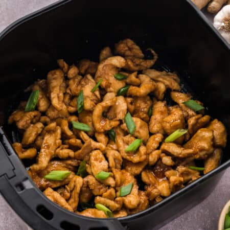 Mongolian chicken in an air fryer basket.
