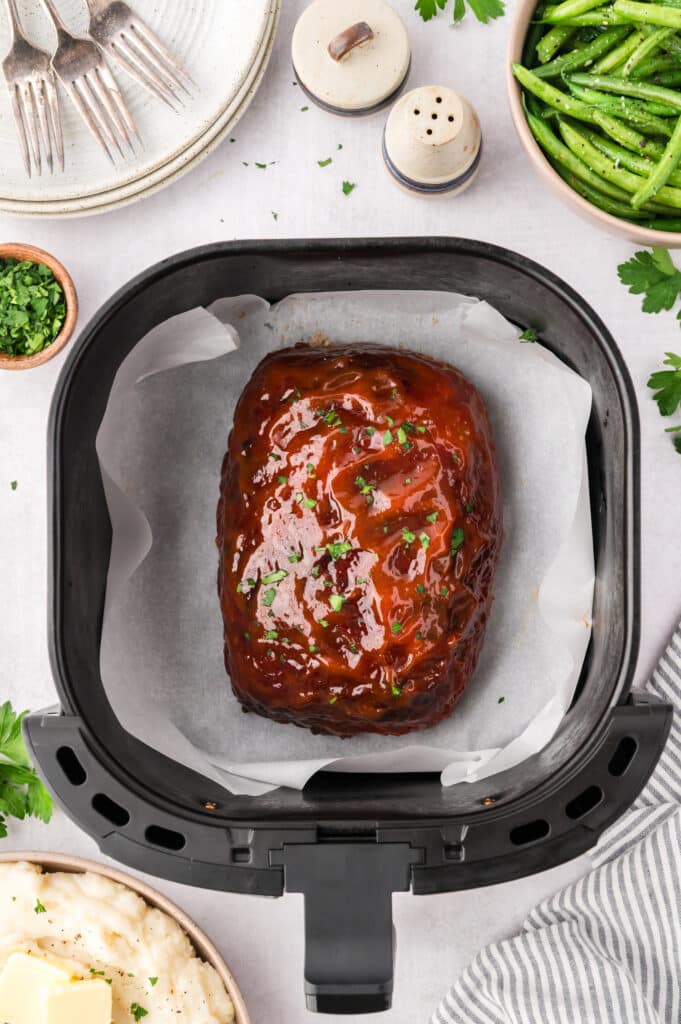 Overhead view of Meatloaf in an air fryer basket with a glaze on top.