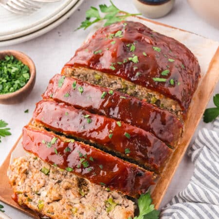 Close up of sliced turkey meatloaf on a small wooden cutting board.