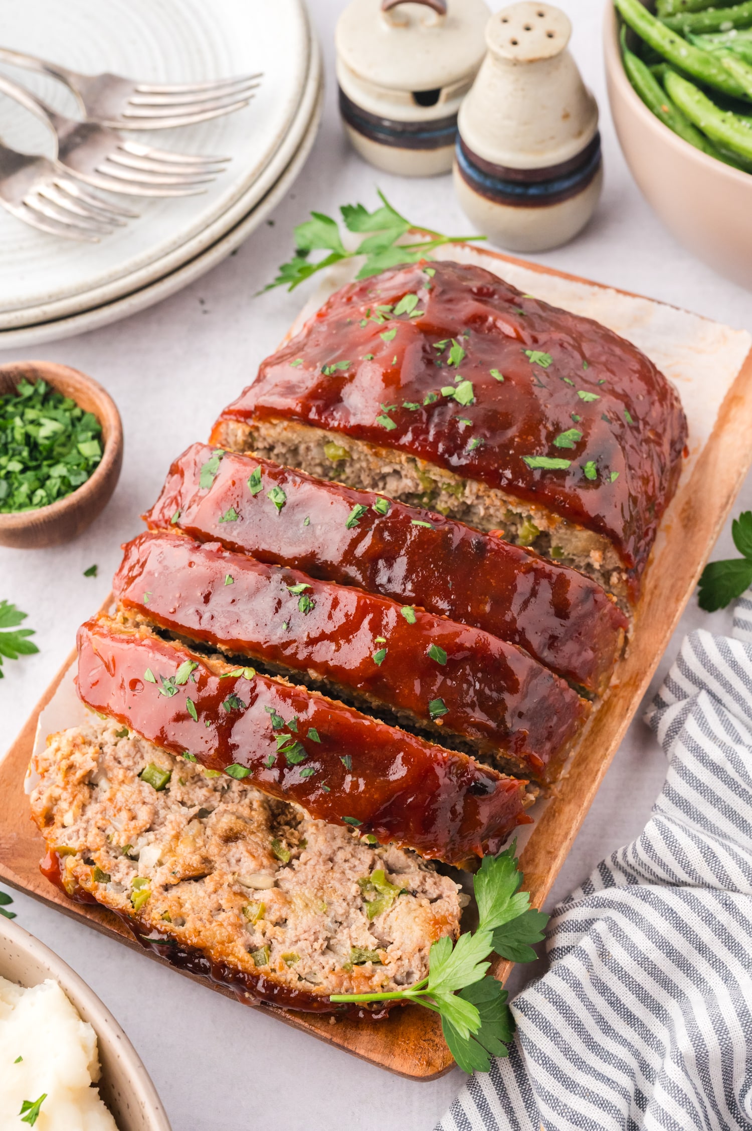 Close up of sliced turkey meatloaf on a small wooden cutting board.