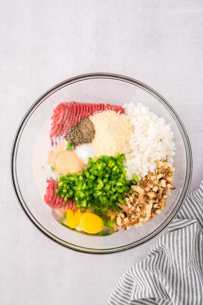 Ingredients for meatloaf together in a clear glass bowl.