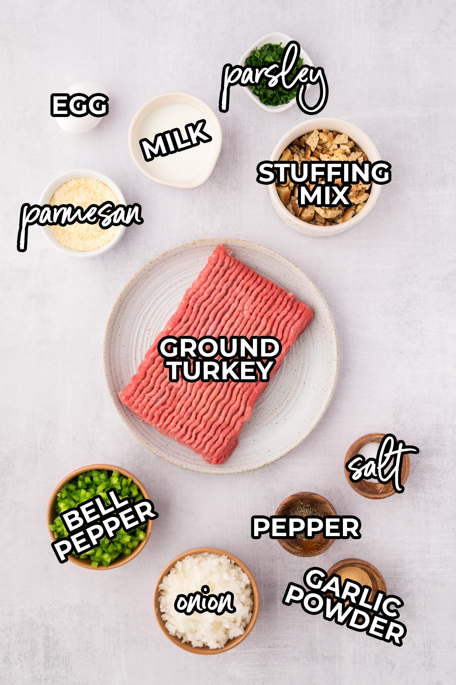 Ingredients for turkey meatloaf on a white countertop each labeled with a text overlay.